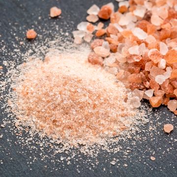 Close-up of pink Himalayan salt granules and a small pile of fine salt.