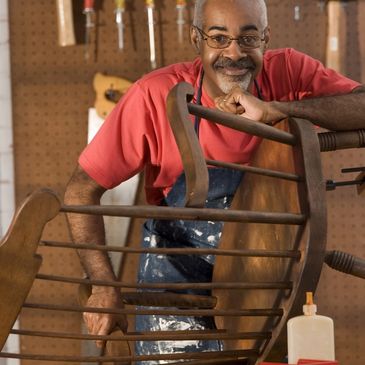 Man restoring a wooden chair in a workshop.