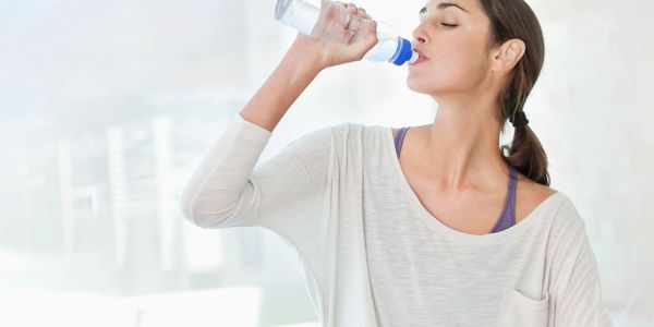 Woman drinking cold bottled purified water.