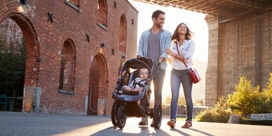 "Young family with baby strolling near historic bridge, safeguarded by Abrams life insurance."