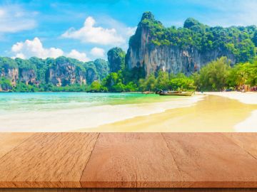Sunny beach with clear water and cliffs.