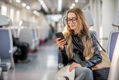 Young woman using phone on public transport.