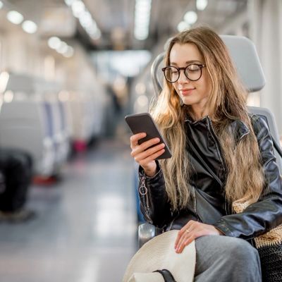 Young woman using phone while sitting on a train.