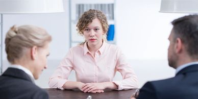 Une femme et un homme en tailleur qui font une entrevue à une jeune candidate blonde