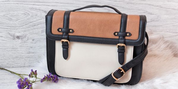Stylish tricolor leather satchel bag with buckles and strap.