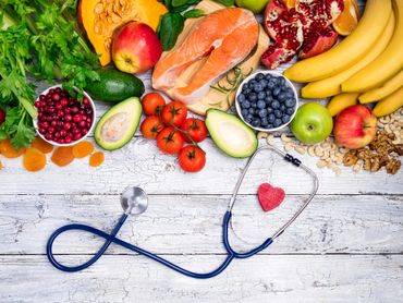 Fresh fruits, vegetables, salmon, and a stethoscope symbolizing healthy living.
