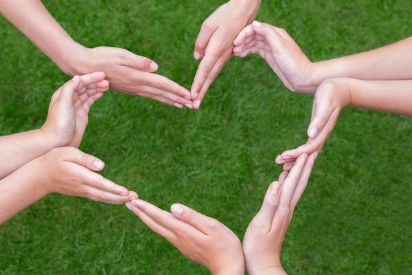 Four people arrange their hands into the shape of one heart