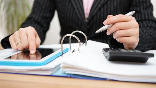 Person using tablet and calculator with documents.