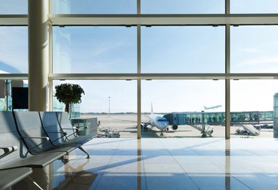 Empty airport waiting area with plane visible outside.