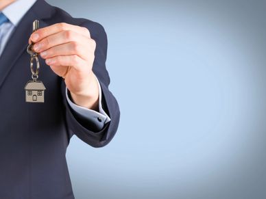 Man in suit holding a key with a house keychain