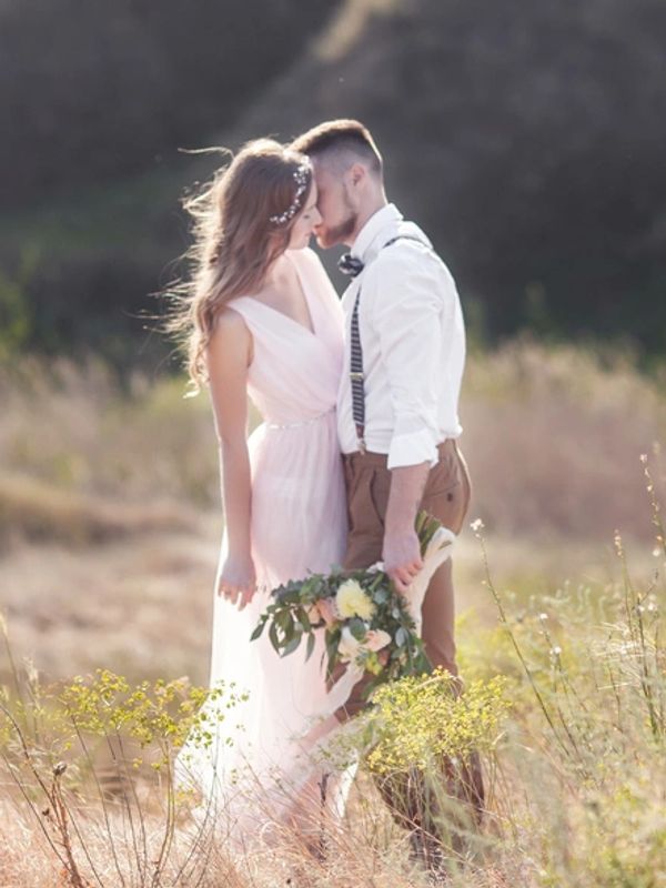 Couple sharing a tender moment outdoors, holding flowers.