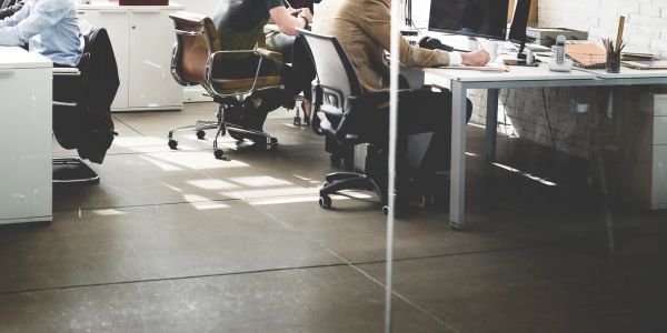Personas trabajando en una oficina moderna con escritorios y computadoras.