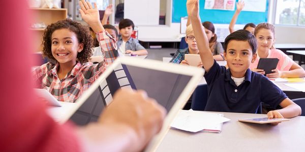 Students in a classroom raising their hands