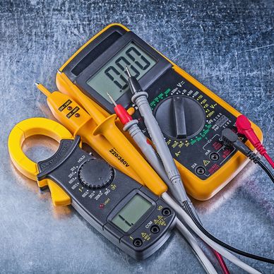 Two yellow digital multimeters with probes on a metallic surface.