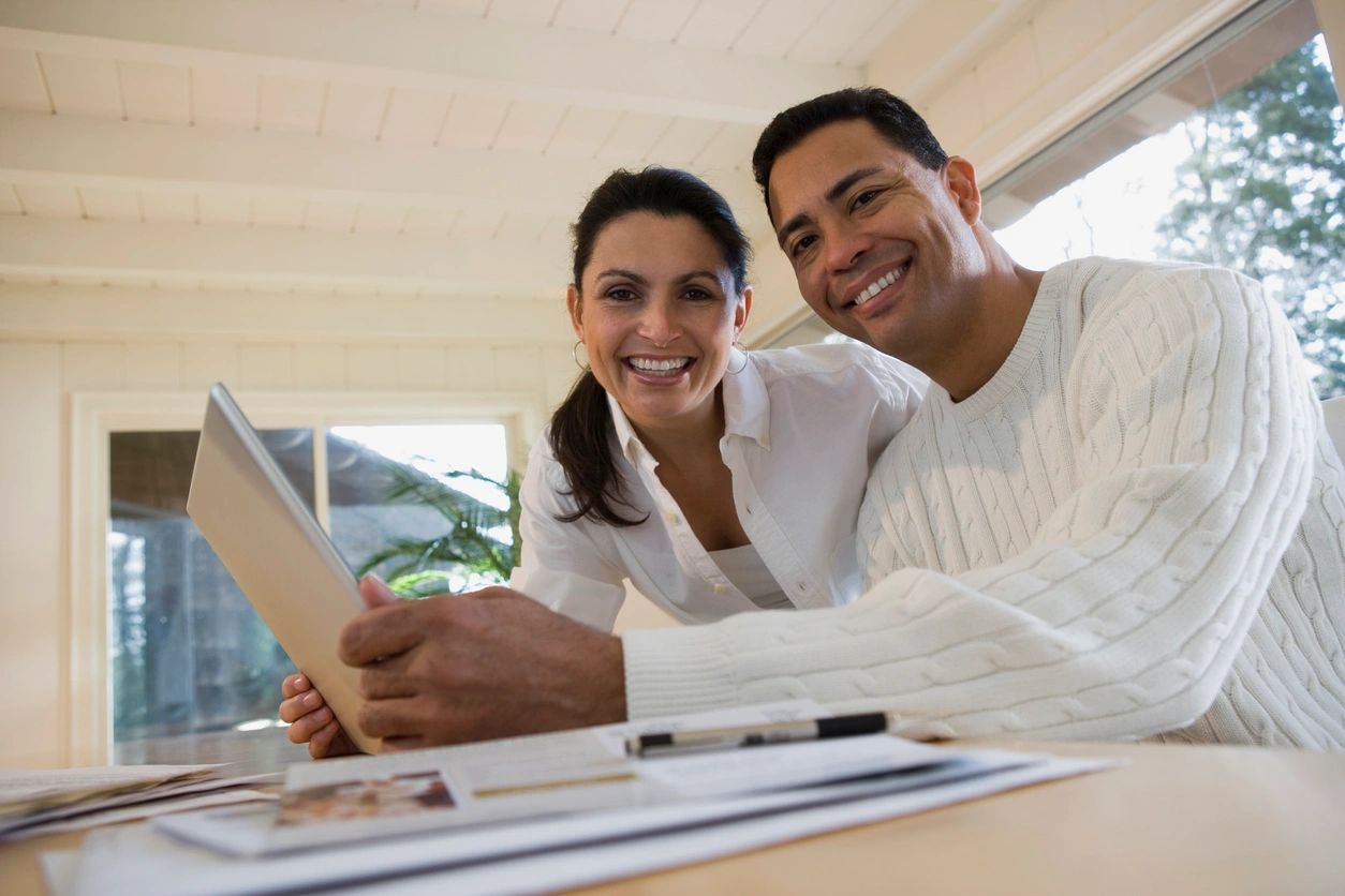 A couple smiles as they review potential real estate deals to invest in remotely.