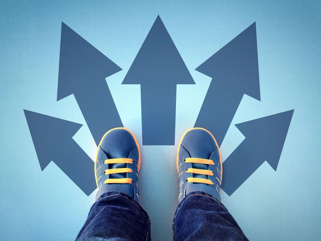 a pair of blue shoes facing 5 different arrows leading in different directions