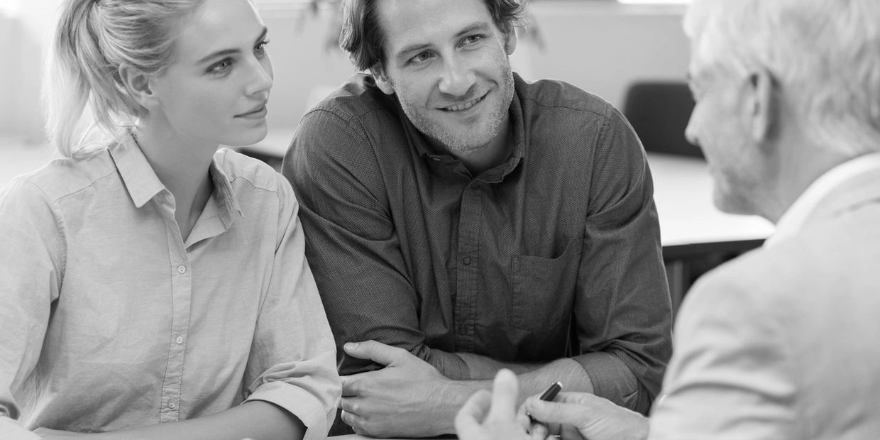 Young couple attentively listening to an older man in a conversation.