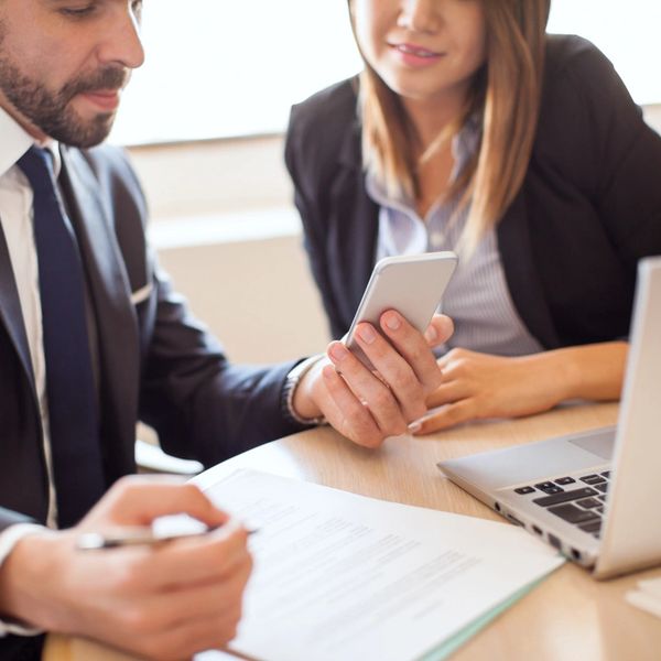 Two professionals reviewing documents and a smartphone during a meeting.