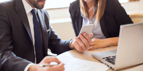 Deux travailleurs de bureau regardant un telephone portable