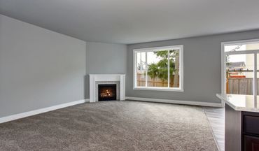 Empty living room with carpet and fireplace.