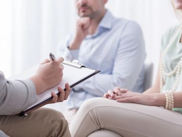A therapist taking notes during a counseling session with a couple.
