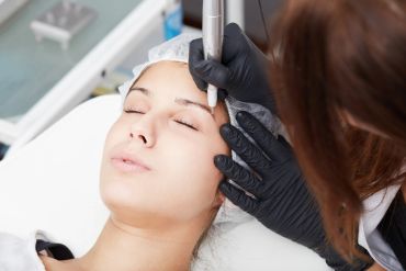 A woman receiving a cosmetic eyebrow tattoo treatment.
