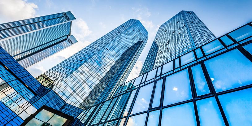 Modern glass skyscrapers reflecting the blue sky from a low angle.