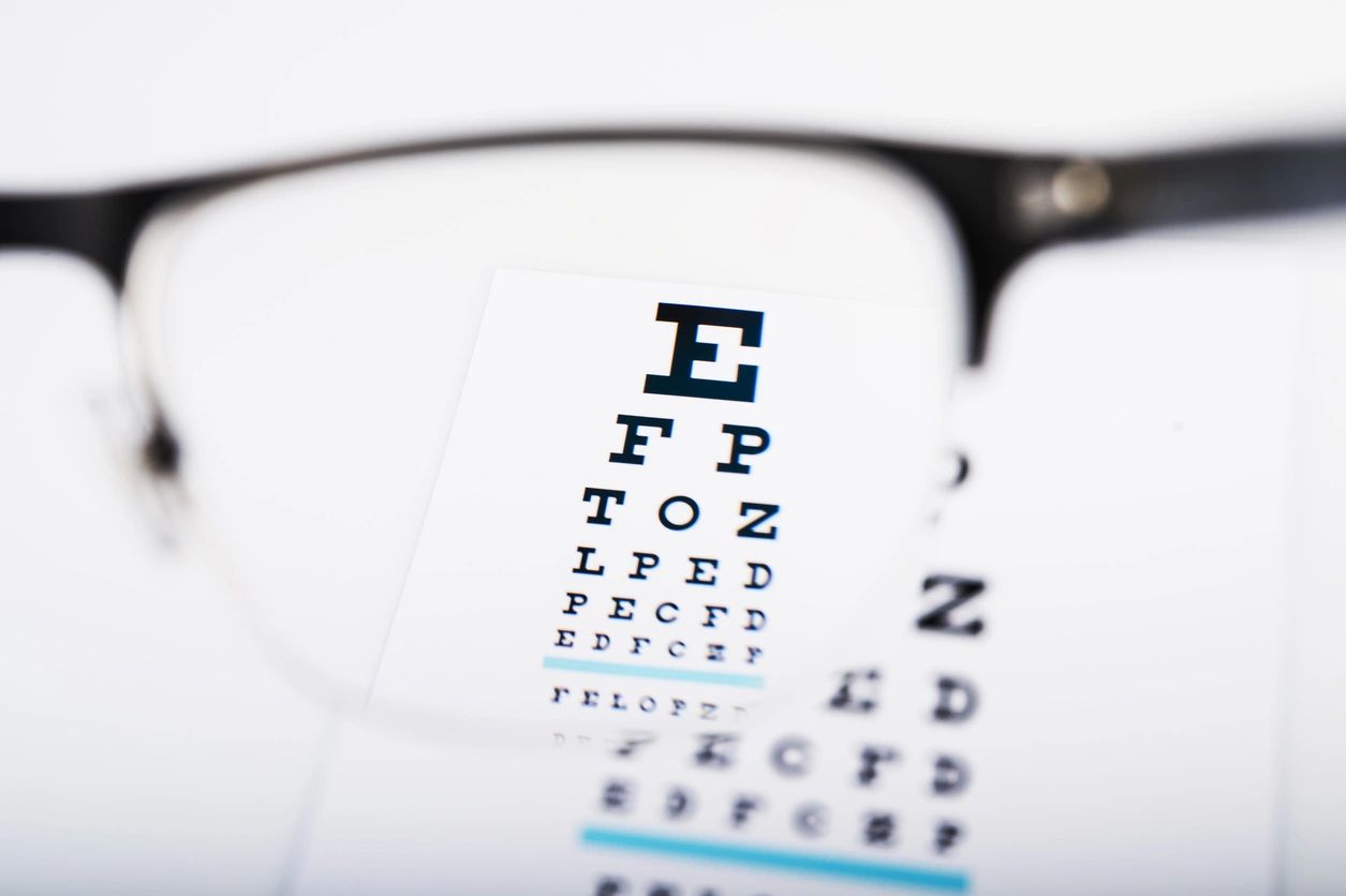 Eyeglasses in focus with an eye chart displaying letters, emphasizing the importance of eye exams for children's myopia management at Fox Run Eye Care.