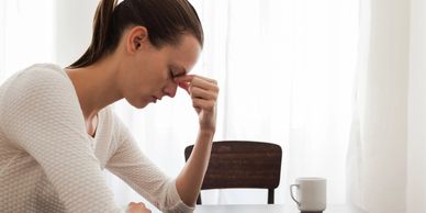 A woman suffering from a headache pinching her nose