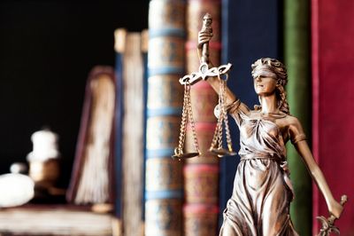 Statue of Lady Justice with old legal books in the background.