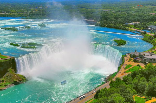 Aerial view of Niagara Falls with mist and a boat below.