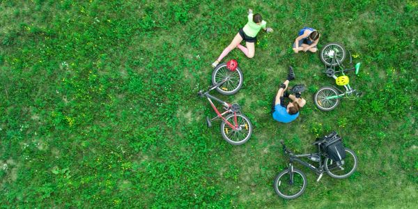 Four people relaxing on grass with bicycles around them.