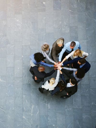 A diverse group of professionals joining hands in a teamwork circle.