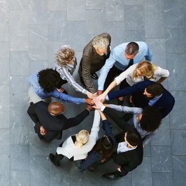 Group of people huddled together with their hands.