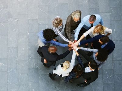 Groupe de personnes unies en cercle avec les mains jointes au centre.