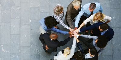 A diverse group of businesspeople joining hands in a teamwork circle.