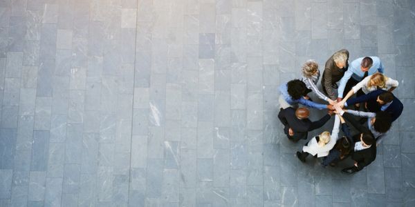 group of people in a circle with right hands touching, view from above