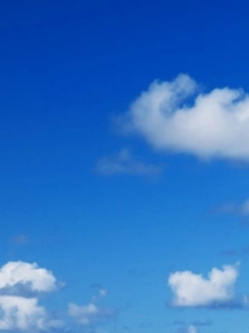 Bright blue sky with scattered white clouds.