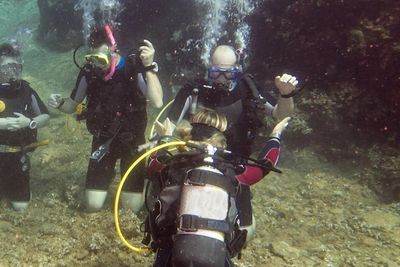 A group of scuba divers underwater near a rocky seabed.