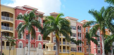 Colorful apartment buildings with palm trees and a fountain in front.