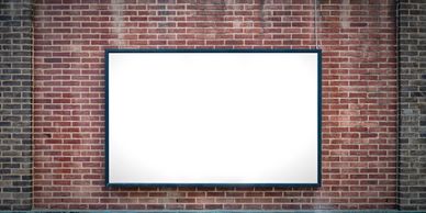 Blank white billboard on a brick wall background.