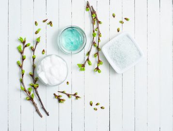 Spa essentials with green plant buds on a white table.