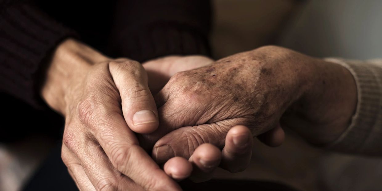 Two hands gently holding each other, symbolizing care and support.