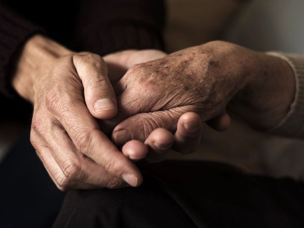 Two elderly hands gently holding each other, symbolizing care and support.