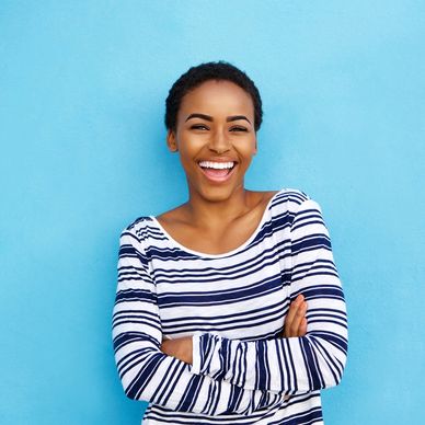 woman with short hair in a striped shirt with her arms crossed, smiling at the camera