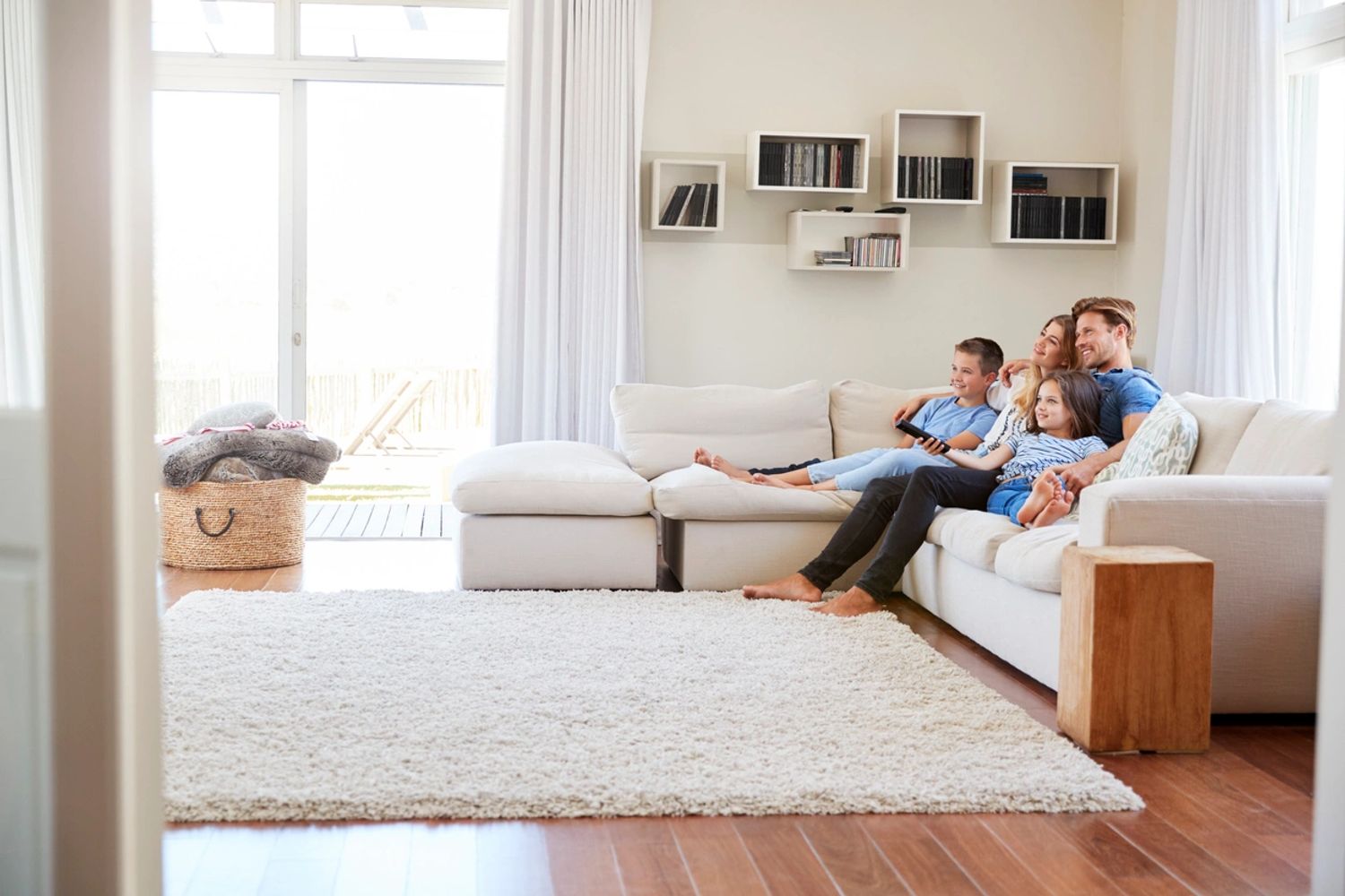 Family relaxing together on a white couch in a bright living room.