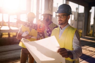 Construction engineers examining blueprints on site.