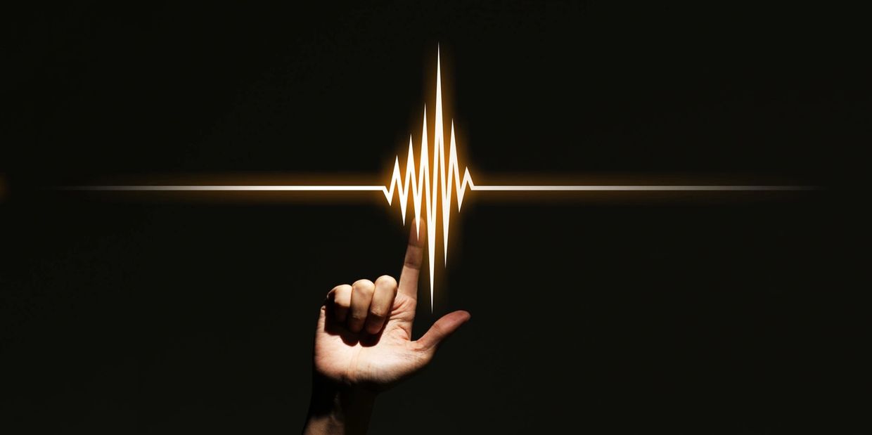 Hand touching a glowing heartbeat pulse line on black background.