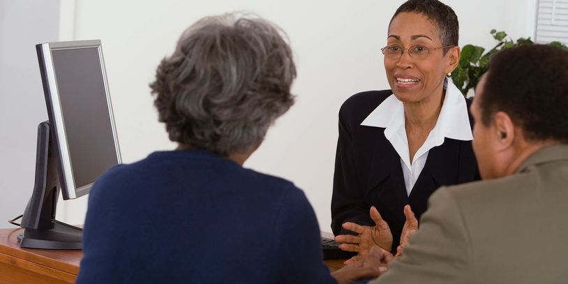 A professional woman consulting with two clients in an office setting.