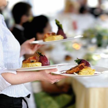 Waiter holding plates of gourmet food at a formal event.